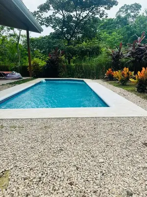 a swimming pool in a garden with a gravel yard at Casa Hilltop Peaceful house 15 minutes from Samara in Sámara
