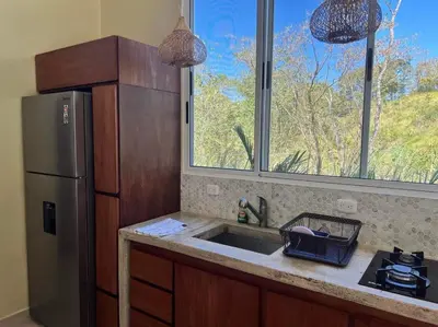 a kitchen with a refrigerator and a sink and a window at Casa Hilltop Peaceful house 15 minutes from Samara in Sámara