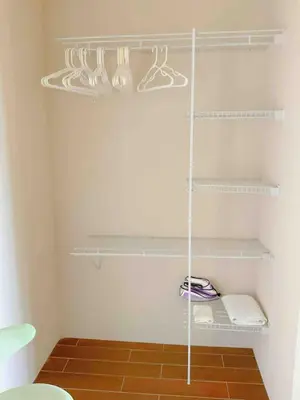 a walk in closet with white shelves and a brown floor at Casa Blanca #1 Beautiful modern beach house in Sámara