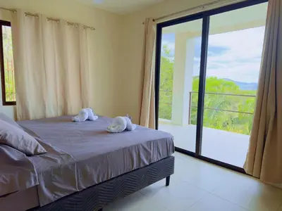 a bedroom with a bed and a large window at Casa Flores Ocean view 10 min to Carrillo in Sámara