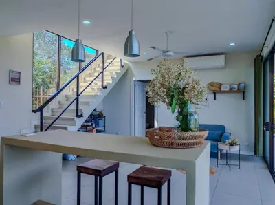 a living room with a staircase and a table with stools at Casa Flores Ocean view 10 min to Carrillo in Sámara