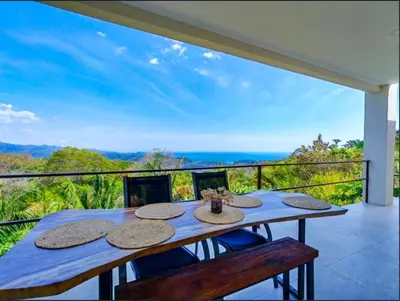 a dining table on a balcony with a view of the ocean at Casa Flores Ocean view 10 min to Carrillo in Sámara