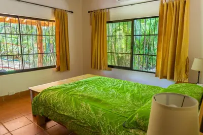 a bedroom with a green bed and windows at Casa Francesca Beautiful house with a large garden in Sámara