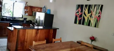 a kitchen with a table and a refrigerator at Aloha Surf Nosara - Casa 'Ohana in Nosara