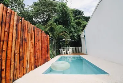 a swimming pool next to a wooden fence at Bamboo House in Herradura with private pool in Herradura