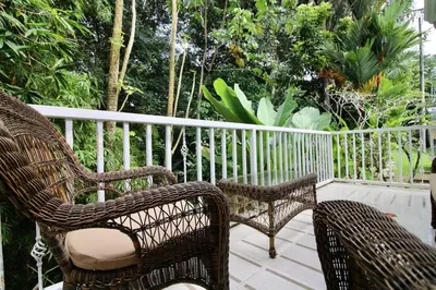 two wicker chairs and a table on a porch at Bamboo House in Herradura with private pool in Herradura