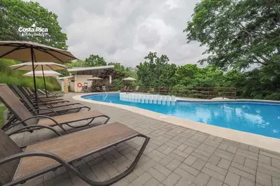 a swimming pool with chairs and an umbrella at Bamboo House in Herradura with private pool in Herradura