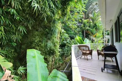 a porch with a grill and chairs and trees at Bamboo House in Herradura with private pool in Herradura
