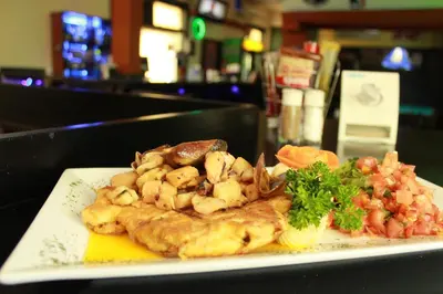 a plate of food with shrimp and vegetables on a table at Sportsmens Lodge - Gentlemen's Club in San José