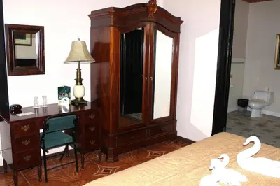 a bedroom with a desk and a dresser with swans on it at Sportsmens Lodge - Gentlemen's Club in San José