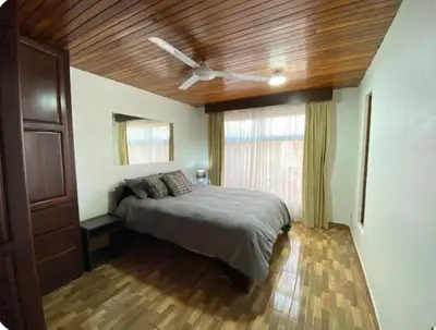 a bedroom with a bed and a ceiling fan at Tico Airport B&B in Alajuela City