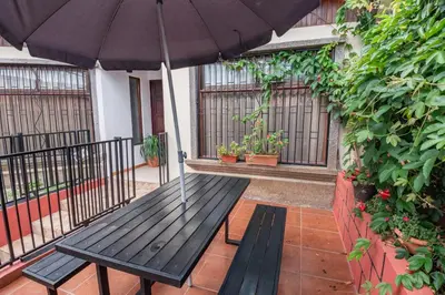 a wooden bench with an umbrella on a patio at Tico Airport B&B in Alajuela City