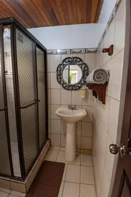 a bathroom with a sink and a shower and a mirror at Tico Airport B&B in Alajuela City