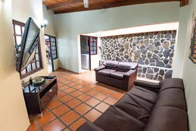 a living room with a couch and a stone wall at Tico Airport B&B in Alajuela City