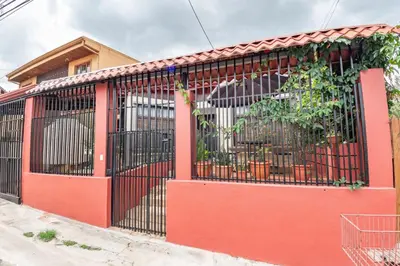 a red gate in front of a building at Tico Airport B&B in Alajuela City
