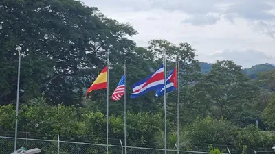 three flags on poles in front of a fence at Home Pura Vida With Cuban Flavor