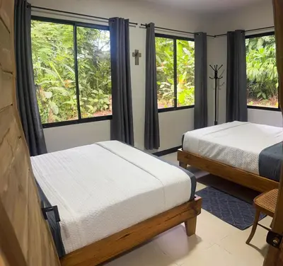 two beds in a room with two windows at Casa Selva Pacifico in Quebrada Ganado