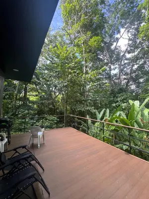 a wooden deck with chairs and trees in the background at Casa Selva Pacifico in Quebrada Ganado