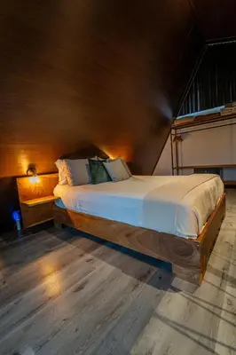 a large bed in a room with a wooden ceiling at Cozy Volcano View Stay Brand New & Hot Tub in Fortuna