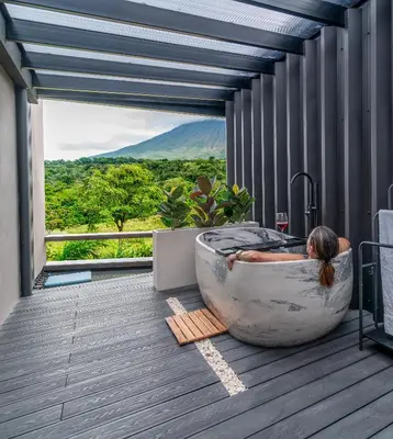 a woman laying in a bath tub in a room with a view at Charming Cabin in La Fortuna wHot Tub Brand new! in Fortuna