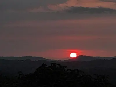 a sunset with the sun setting over the mountains at Casa Rústica Rancho de Lía- Vacacional in Orotina