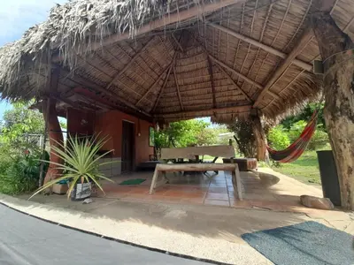 a hut with a picnic table under a straw umbrella at Casa Rústica Rancho de Lía- Vacacional in Orotina