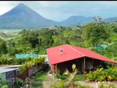 a red roofed house with a mountain in the background at Casa Lago in El Castillo de La Fortuna