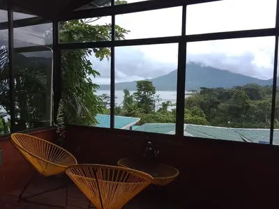 a room with a large window looking out at the mountains at Casa Lago in El Castillo de La Fortuna
