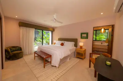 a bedroom with a bed and a chair and a window at Casa Contento - luxury 3bdr home near Santa Teresa in Boca de Ario
