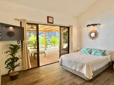 a bedroom with a bed and a sliding glass door at Passion For Surfing Apt Playa Guiones in Playa Guiones