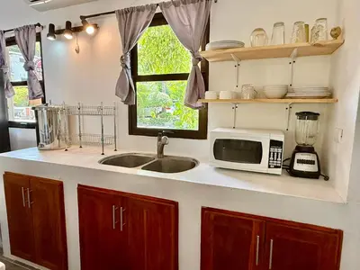 a kitchen with a sink and a microwave at Passion For Surfing Apt Playa Guiones in Playa Guiones