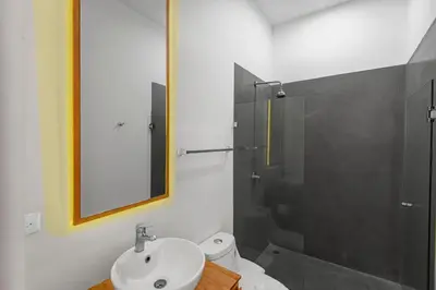 a bathroom with a sink and a shower with a mirror at Jacó Condo 2 BR, Pool & families in Jacó