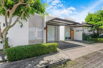 a white house with a tree in front of it at Jacó Condo 2 BR, Pool & families in Jacó