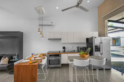 a kitchen with white appliances and a table and chairs at Jacó Condo 2 BR, Pool & families in Jacó