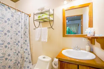 a bathroom with a sink and a toilet and a mirror at Casa Plumeria-Aloha Surf Nosara in Nosara