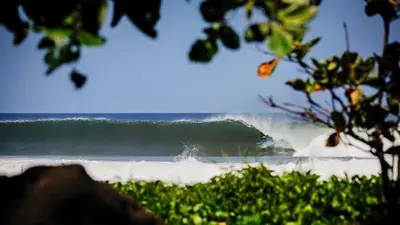 a surfer riding a large wave in the ocean at Casa Mango- family friendly 2 Bedroom, 2 Bath in Nosara
