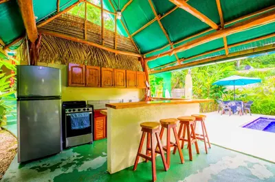 a kitchen with a bar with stools in it at Casa Mango- family friendly 2 Bedroom, 2 Bath in Nosara