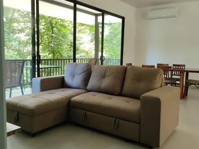 a brown couch in a living room with windows at Villa del Río in Savegre
