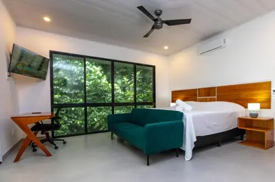 a bedroom with a bed and a couch and a window at Villa del Río in Savegre