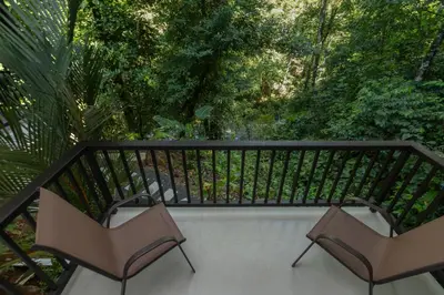two chairs on a balcony with trees in the background at Villa del Río in Savegre