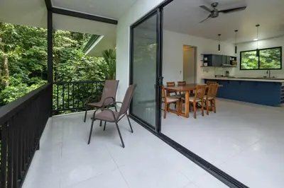 a balcony with a table and chairs and a kitchen at Villa del Río in Savegre