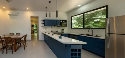 a kitchen with blue cabinets and a table with chairs at Villa del Río in Savegre