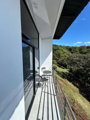 a balcony of a house with two chairs on it at Poás Natural in Alajuela City