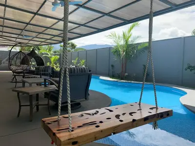 a porch with a swing and a swimming pool at Villa Ballena de Uvita in Uvita