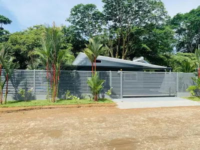 a house with a fence and palm trees at Villa Ballena de Uvita in Uvita