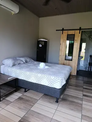 a bed in a room with a wooden floor at Maracuyá Garden Stanza 1 in Parrita