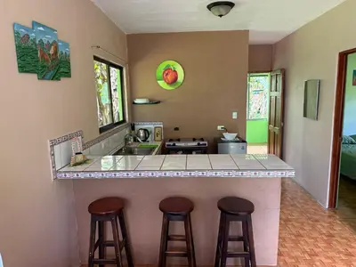 a kitchen with three bar stools at a counter at NeyHouse in Sarapiquí