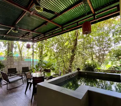 a patio with a koi pond and a table and chairs at Jungle House with Private Jacuzzi in Uvita