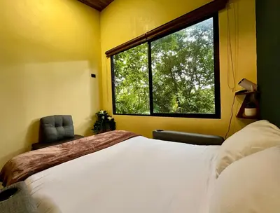 a bedroom with a large bed and a window at Jungle House with Private Jacuzzi in Uvita