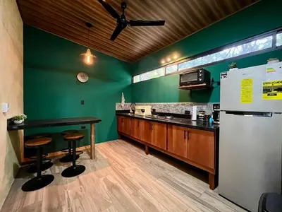 a kitchen with green walls and a counter with stools at Jungle House with Private Jacuzzi in Uvita